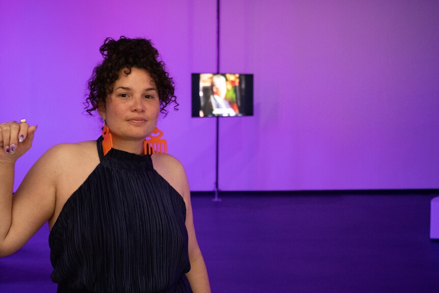 Roberta Joy Rich in her exhibition The Purple Shall Govern with TV screen in background