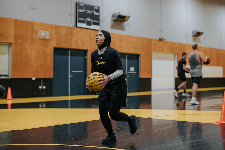 Sabera goes to take a shot on an indoor basketball court.