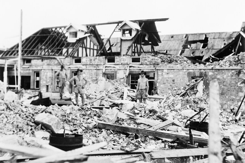 Australian troops inspect bomb damage caused by Japanese air raids.