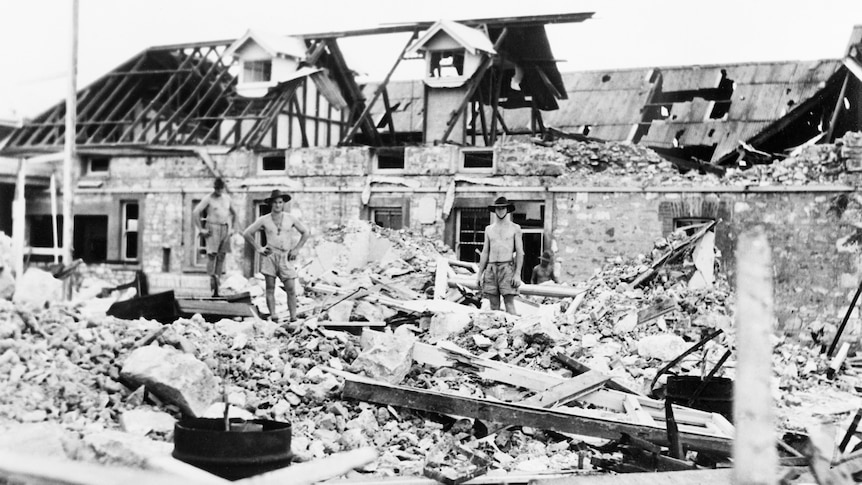Australian troops inspect bomb damage caused by Japanese air raids.