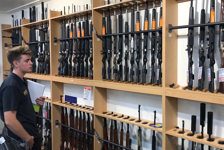A man looks at a row of firearms on display at Gun City gun shop in Christchurch.