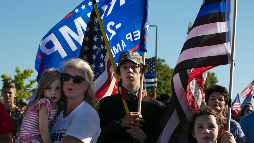 A woman and children hold flags at a protest.