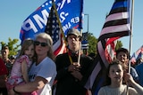 A woman and children hold flags at a protest.