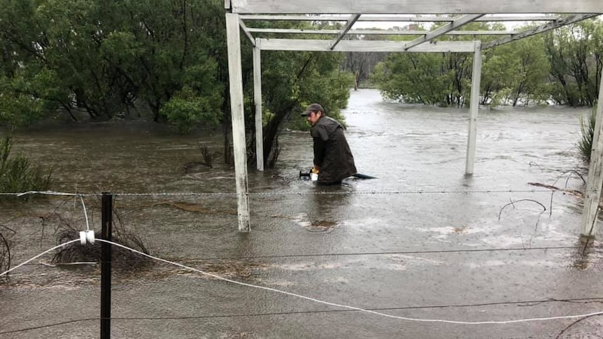 Mick is up to his knees in water as rain falls down.