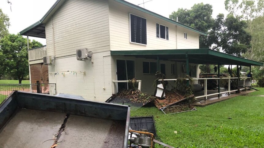 A damaged house with fallen fences after being inundated by flood waters.