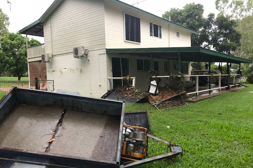 A damaged house with fallen fences after being inundated by flood waters.