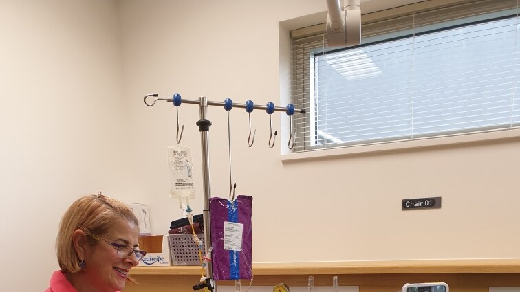 Breast care nurse sits in clinic room, smiling at her patient who is seated next to her.