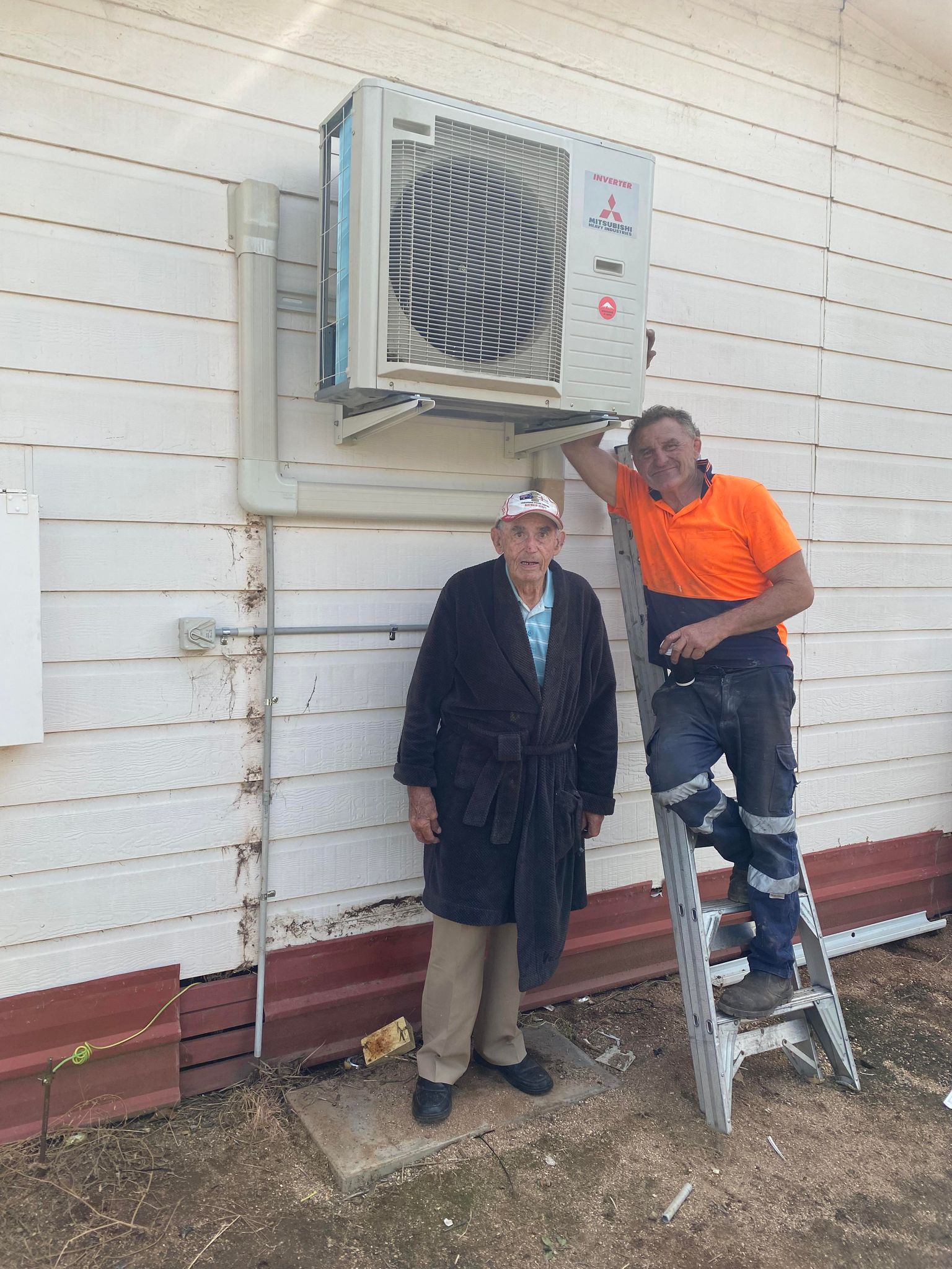 Two men standing next to a new air-conditioning unit