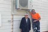 Two men standing next to a new air-conditioning unit.