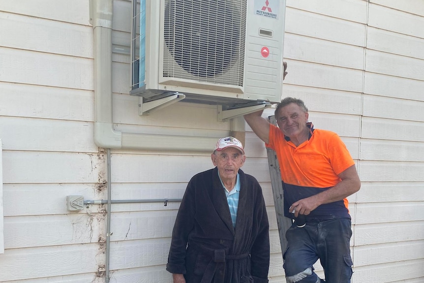 Two men standing next to a new air-conditioning unit