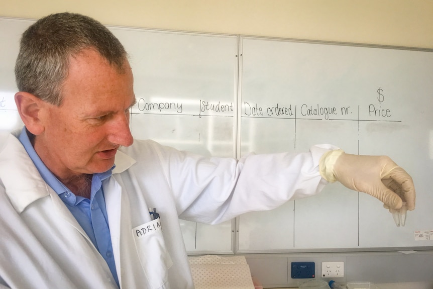 Professor Adrian Linacre in a lab coat holds two small vials.