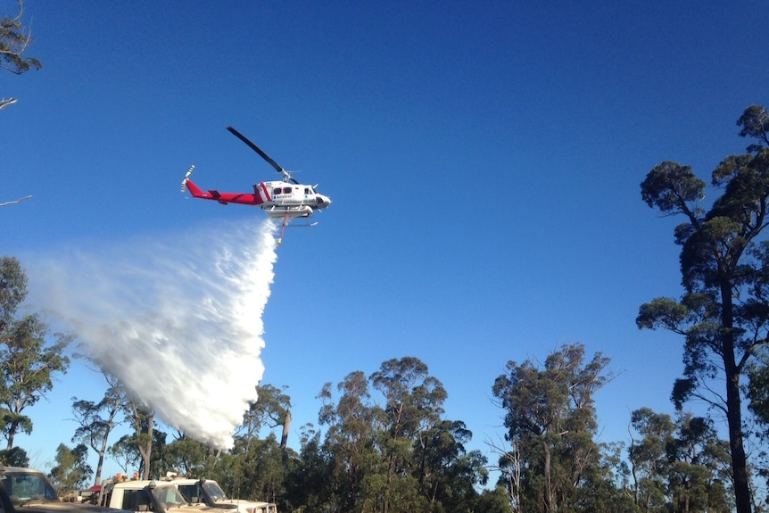 Waterbombing helicopter dumps load on fire