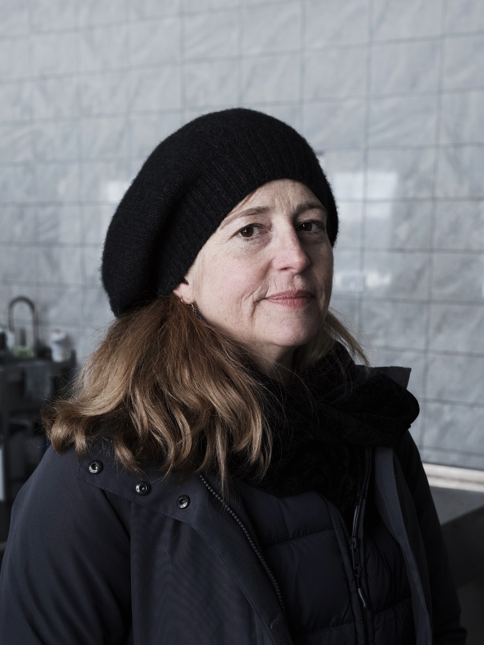 A woman looks at the camera with a neutral expression.