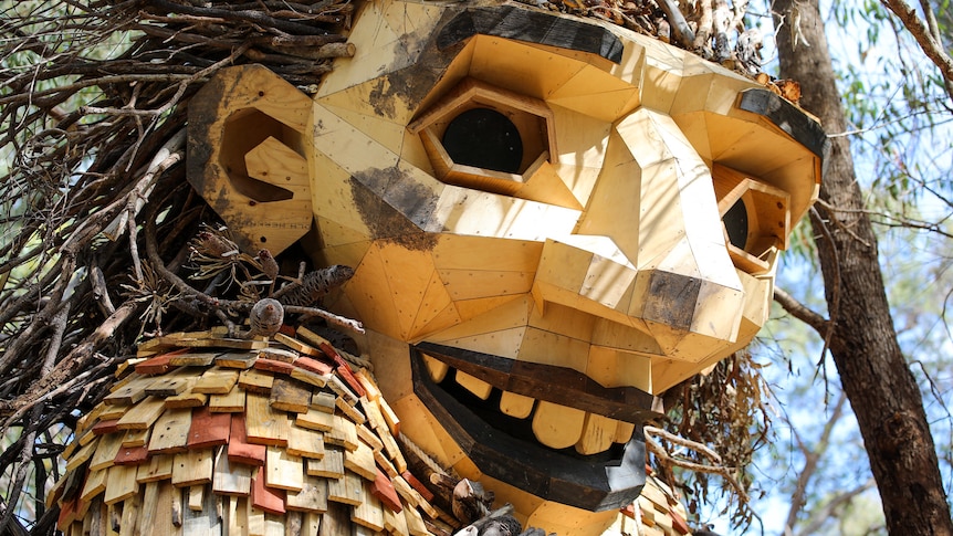 A close up of a massive wooden sculpture of a human face