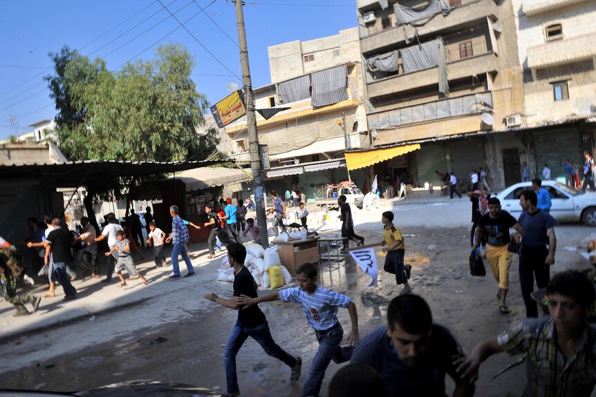 Syrians run for cover as a helicopter hovers over Aleppo.