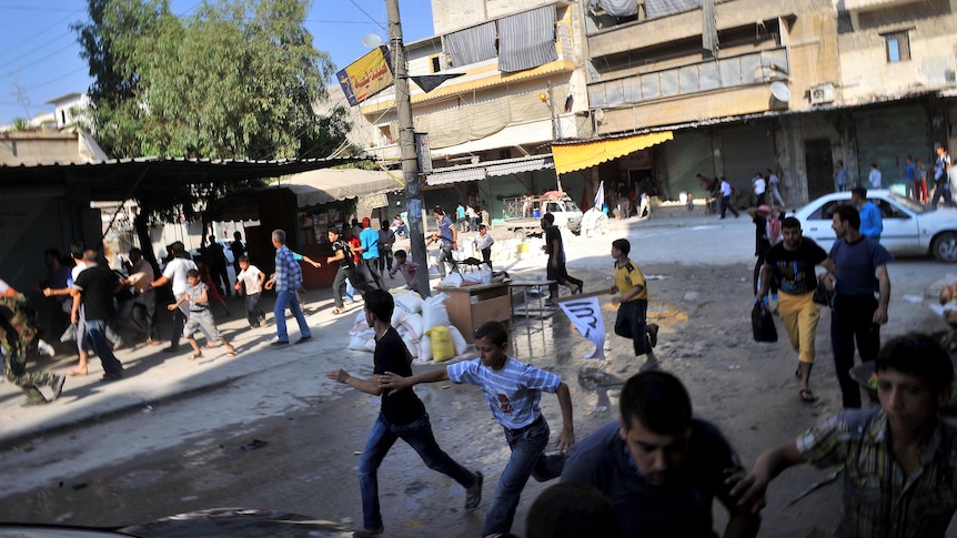 Syrians run for cover as a helicopter hovers over Aleppo.