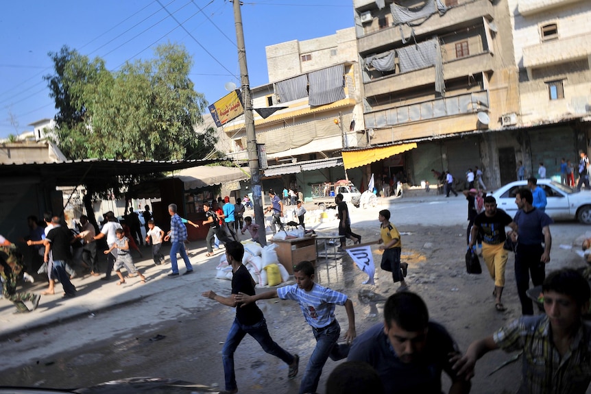 Syrians run for cover as a helicopter hovers over the northern city of Aleppo.