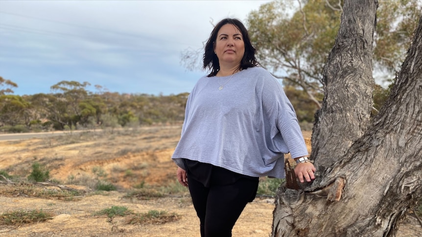 Woman standing in front of tree outside rural background