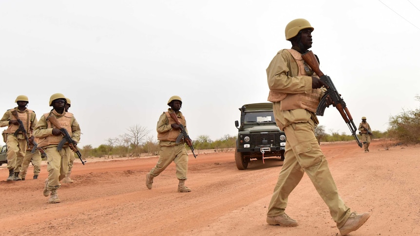 Soldiers in Burkina Faso crossing a road.