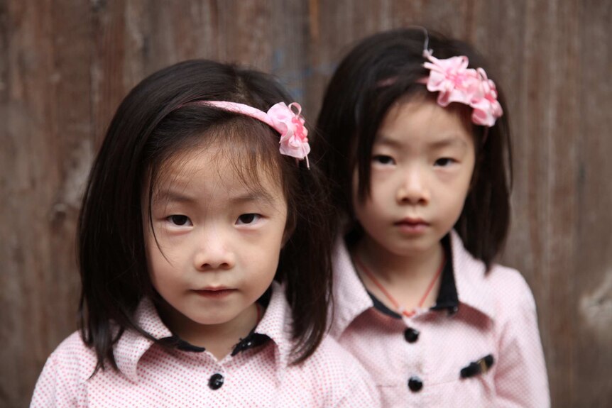 Two twins pose on a street in Tucheng.