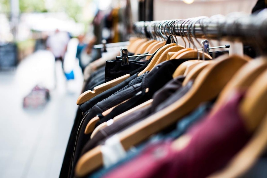 Clothes hanging on a rack in unidentified store.