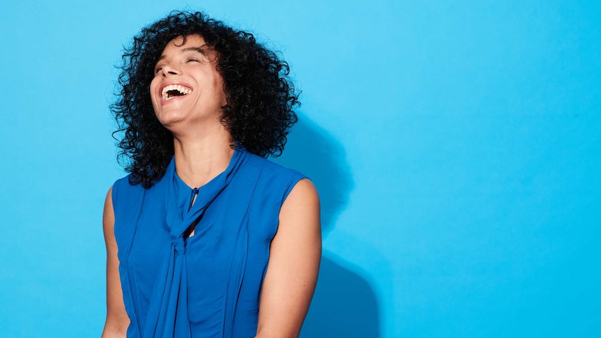 woman smiling in front of a blue background