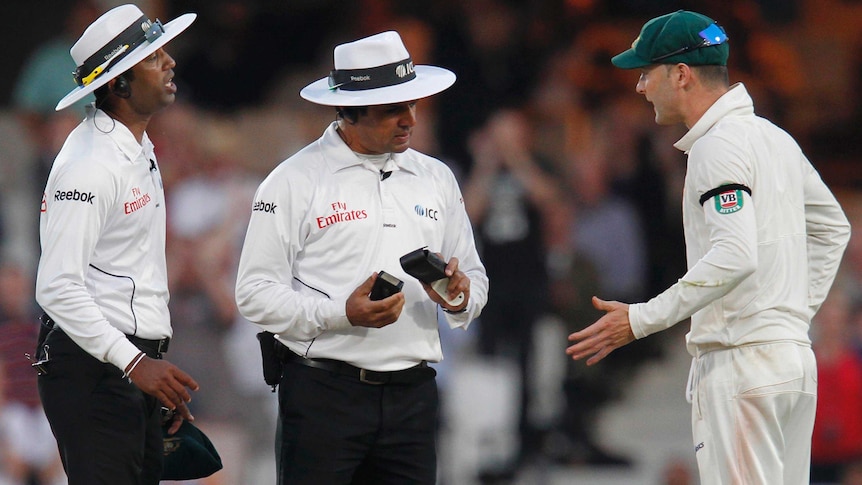 Michael Clarke talks with the umpires before play was stopped due to bad light.