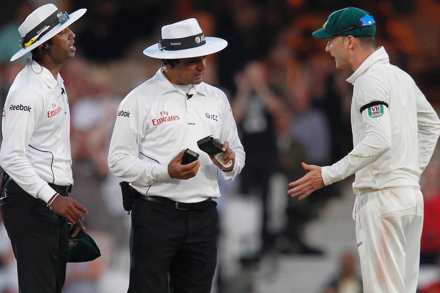 Michael Clarke talks with the umpires before play was stopped due to bad light.