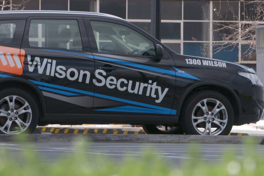 A black SUV with Wilson Security on its side parked in a carpark