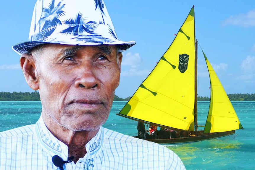 A Cocos Malay man wearing a hat looks pensively up, a yacht with yellow sails on tropical blue water in the background.