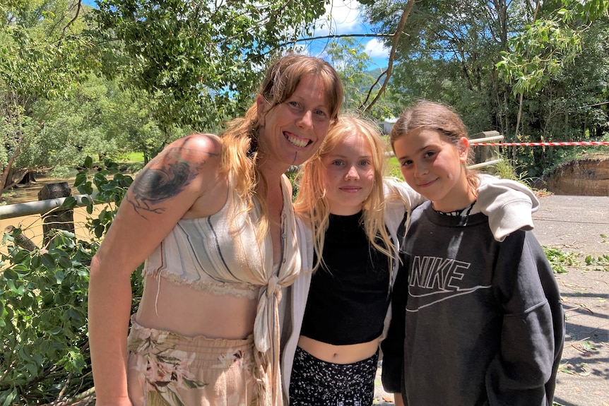 Woman and two girls pose for camera with greenery in the background