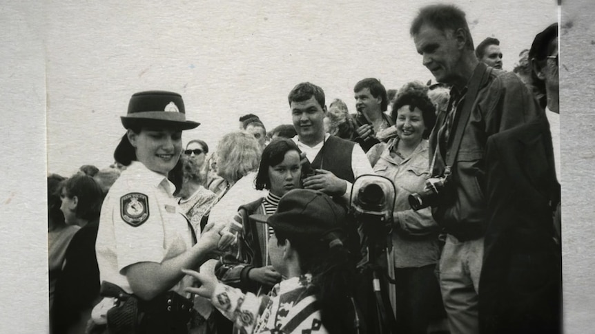 Black and white image of a police woman greeting a crowd