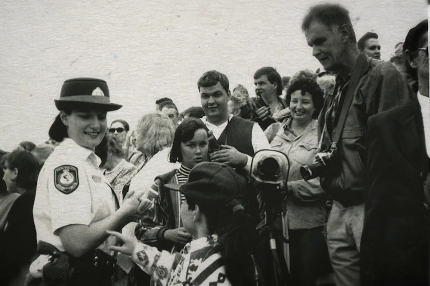 Black and white image of a police woman greeting a crowd