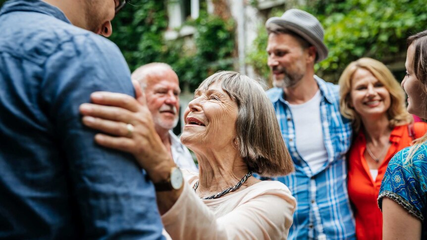 group of people interacting with woman looking up to greet man