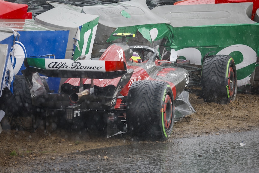 A crashed F1 car in a tyre barrier with the driver still in the cockpit.