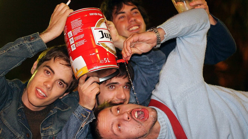 Boys drink out of a beer keg