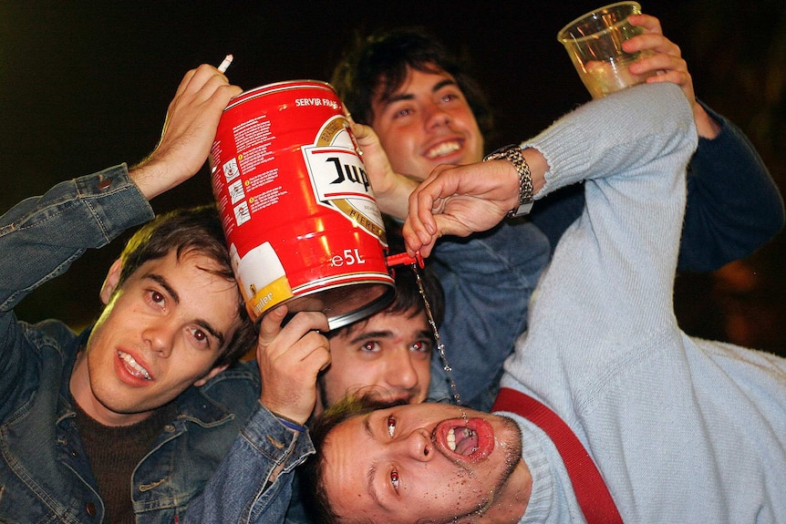 Boys drinking out of beer keg