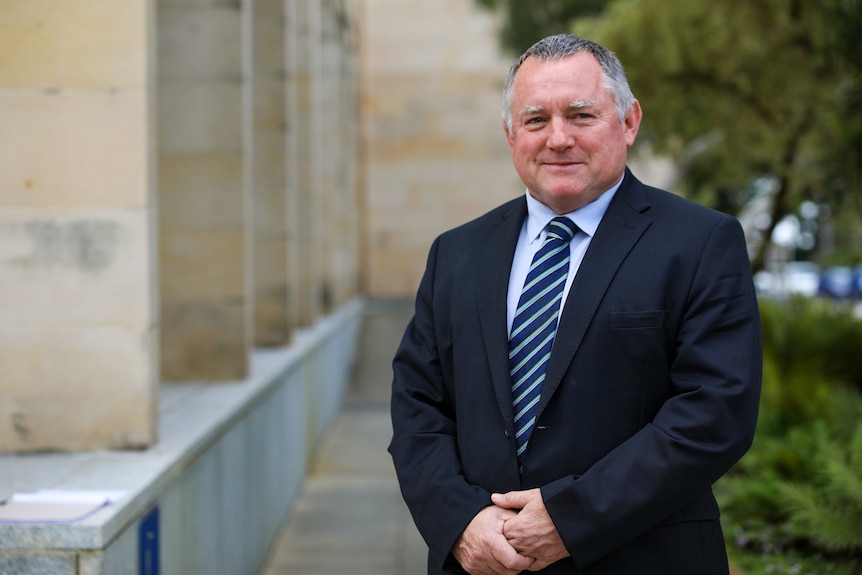 A man in a suit and tie standing outside WA's parliament house. 