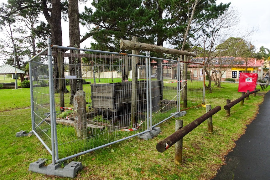 A fenced off monument with a wooden cart.