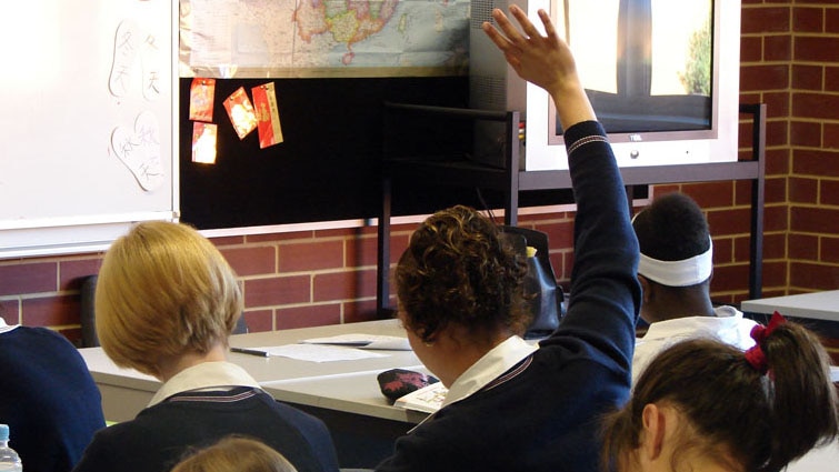 Girl raises hand in high school classroom