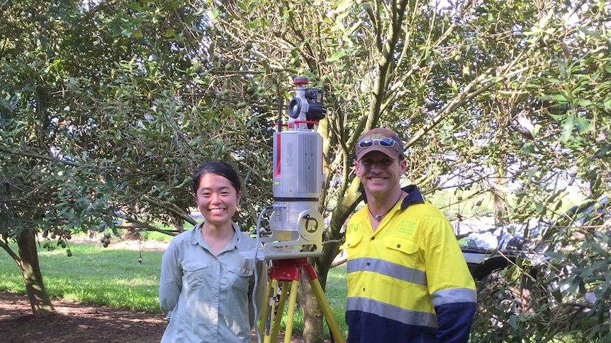 A woman and a man stand either side of a piece of equipment.