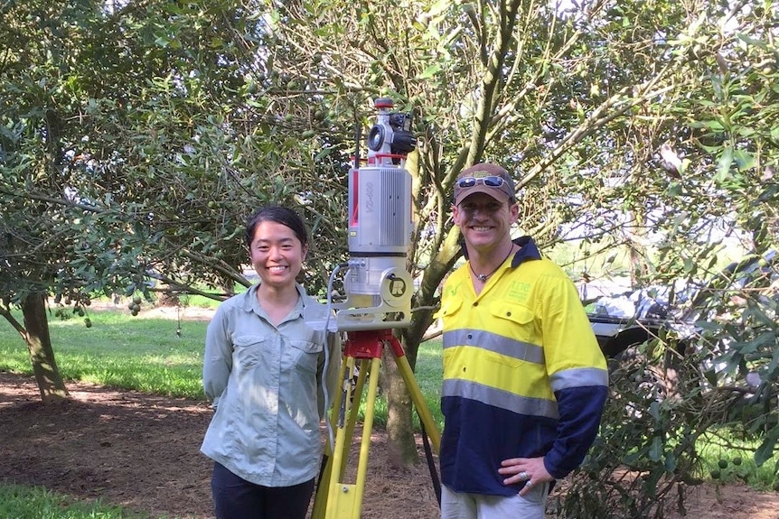 A woman and a man stand either side of a piece of equipment.