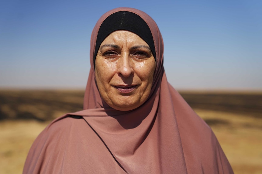 Portrait of Hiam Zahab standing in front of field in Syria near the al-Hawl refugee camp