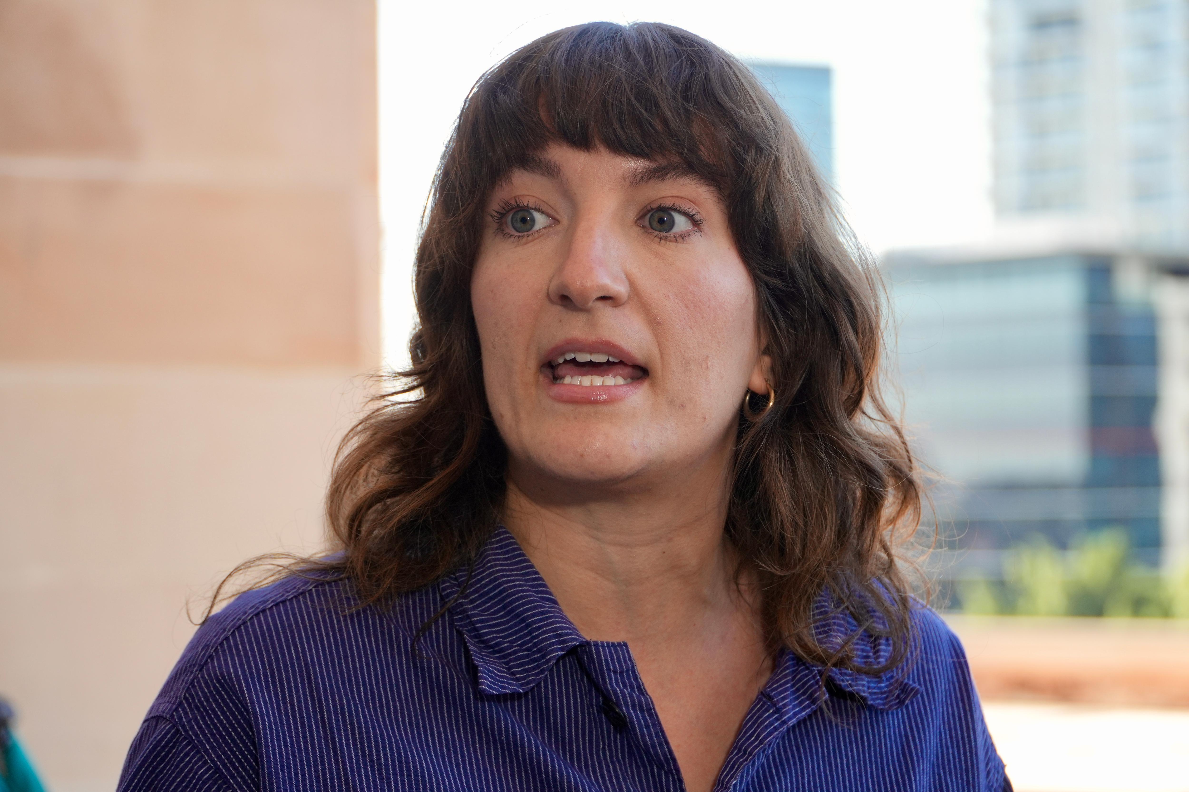 A woman in a navy blue shirt speaks.