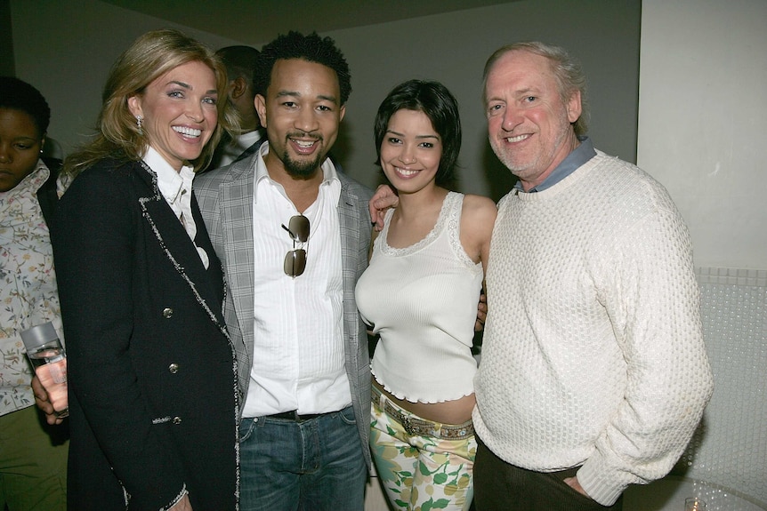 Fraudster Jack Utsick standing with music star John Legend, he is on the right of the photo wearing a woollen jumper, smiling.