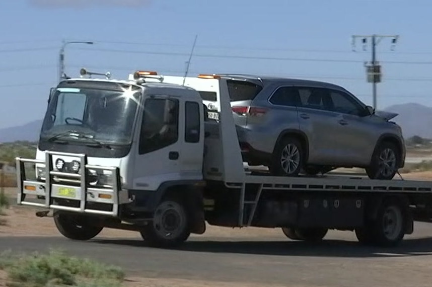 A grey four-wheel drive on the back of a tray tow truck