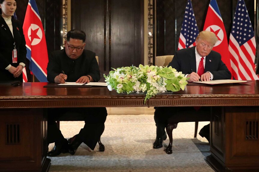 US President Donald Trump and North Korea's leader Kim Jong Un sign documents.