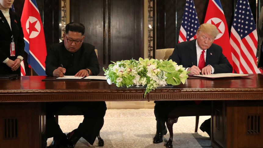 US President Donald Trump and North Korea's leader Kim Jong Un sign documents.