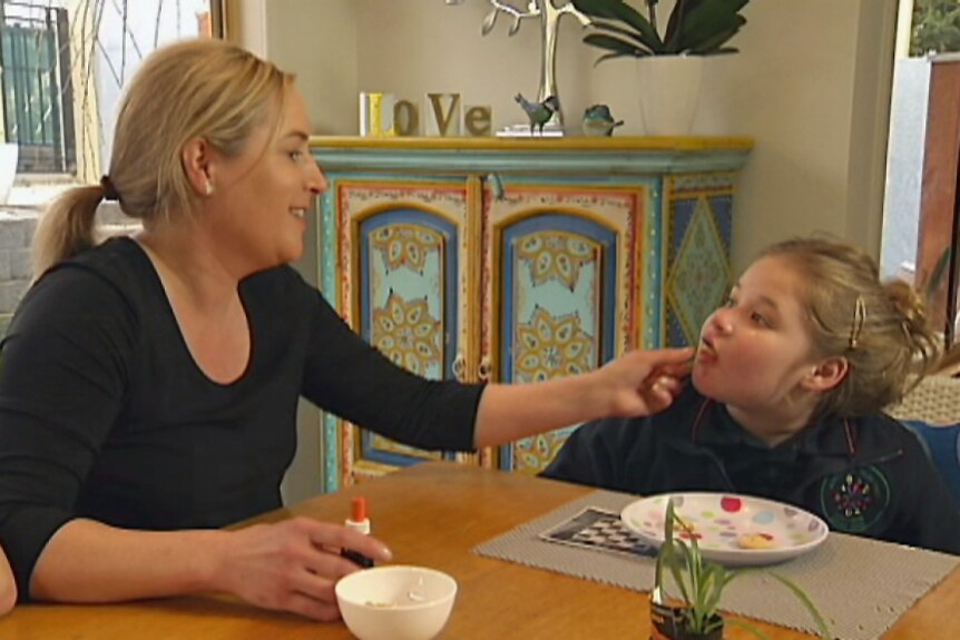 Nicole Cowes administers cannabis oil drops to her daughter Alice.