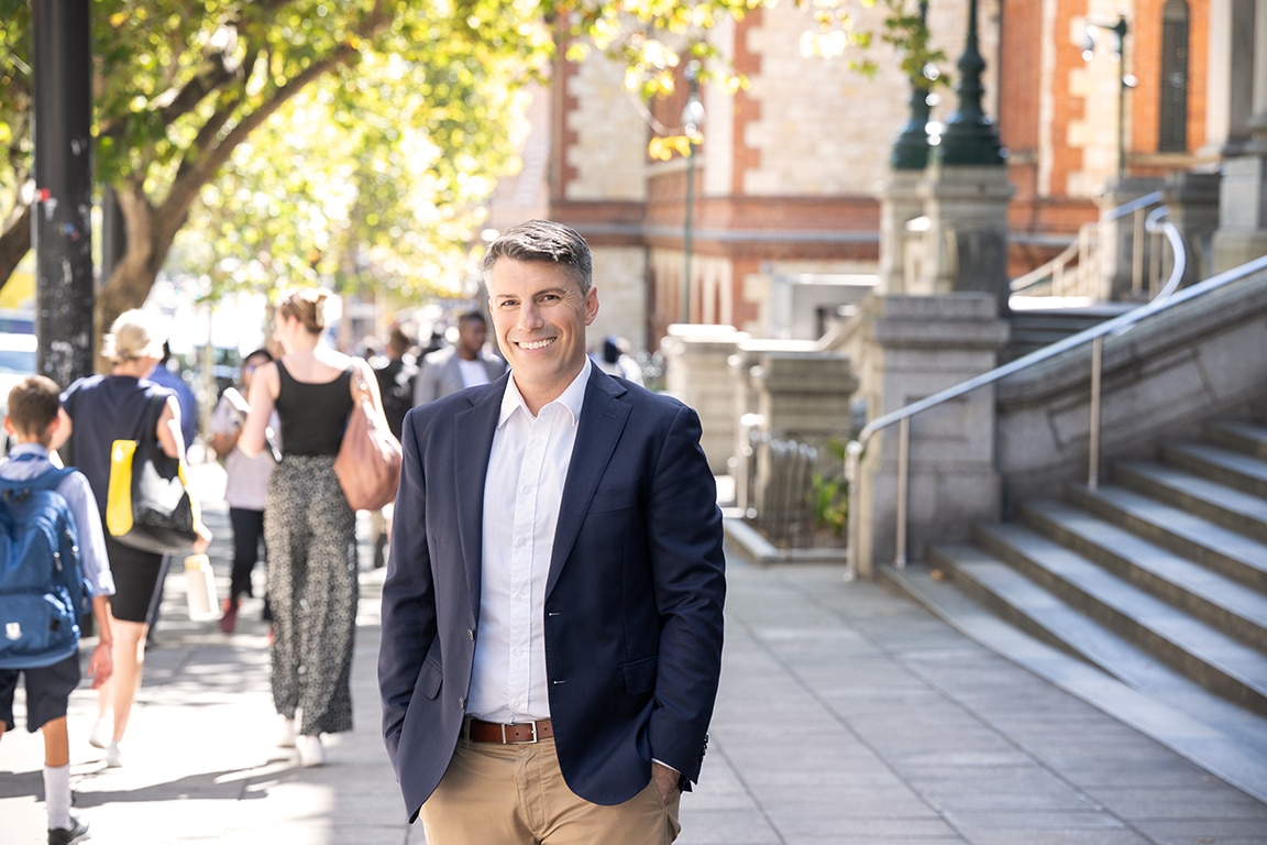 Male standing on city footpath with passers-by
